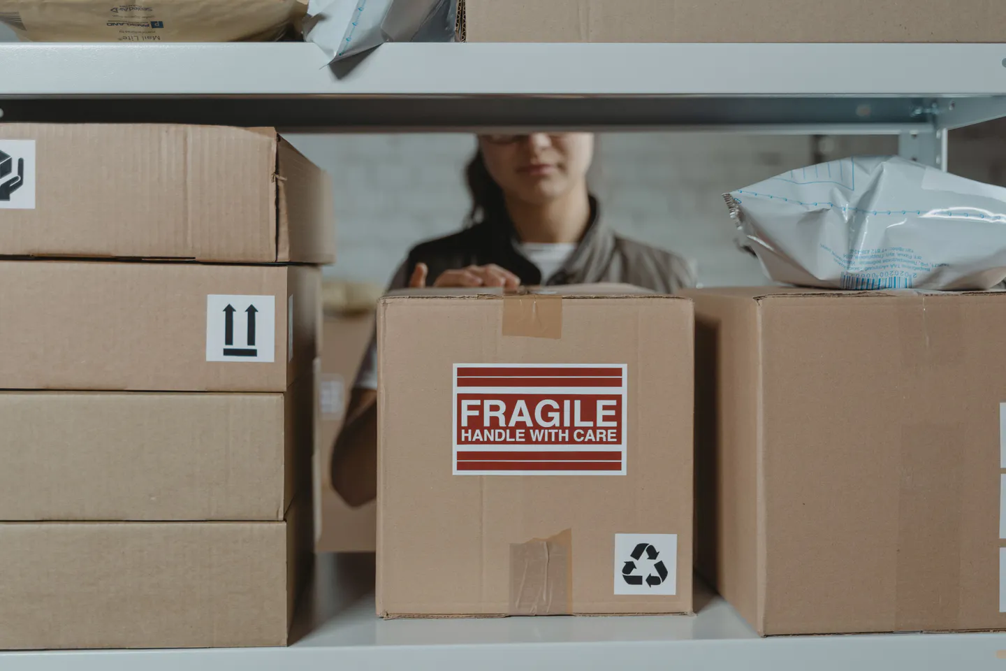 Worker preparing labeled cartons on warehouse shelving